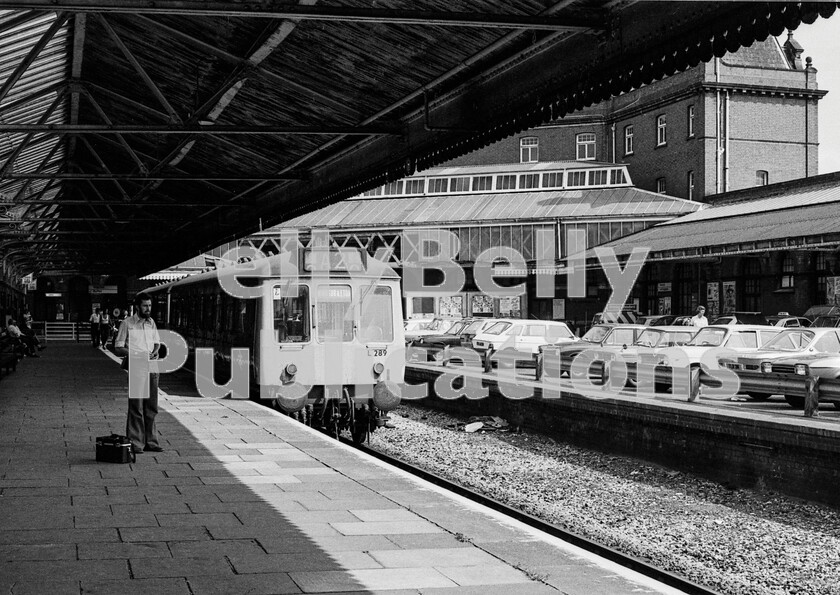 LPPC DSL BW 0896 
 The station at the end of the short Slough to Windsor branch was palatial in size and breadth of planning, yet was only ever an elaborate branch terminus here occupied by a Southall-based two car DMU set consisting of a single-unit Class 121 (56289) and a non-powered driving trailer. That the shot was taken before the UK publics obsession with German cars took hold can be seen by the single BMW CSi in the car park along with a Ford Capri 2, a Mini Clubman Estate, two Triumphs, a 1300 and a Herald, two Austin Maxis and a Toyota Crown Custom Estate. 
 Keywords: BR, Western, Windsor, Class 121, L289, 56289, DMU, Passenger