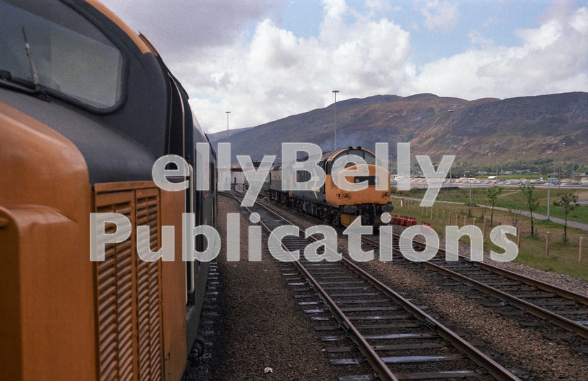 LPAP-DSL-CO-0131 
 37111 'Loch Eil Outward Bound' enters Fort William on the 0950 from Glasgow, as 37191 'International Youth Year' is seen with an ETHEL and the sleeper stock, 28th May 1985. 
 Keywords: BR, Midland, LMS, Scotland, Fort William, Diesel, BR, Passenger, Colour, Class37, 37111, D6811, 37191, D6891, MR, LE, 1985