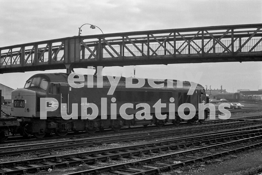 LPPC DSL BW 0340 
 The Peaks were maids of all work on the Midland Lines and here a Class 46 number 46018, which was at this time allocated to Cardiff Canton, waits on the goods lines adjacent to Derby station with a lowly freight service waiting to head south. The footbridge was well-known by enthusiasts lucky enough to be granted access to Derby Works. For many years the pilot-scheme diesels 10201-3 were stored here in the open after withdrawal. To the right and behind the loco is Etches Park depot and in the far background on the right is the British Rail Research Centre. Standing outside are a Baby Deltic and a Warship locomotive, long since past their sell-by dates but used for experimentation and testing by the Centre. The NSU Prinz 4 rear-engined saloon, in front of the Triumph 1500 in the car park, is a slightly left of centre choice of small car in this period before we joined the EU.