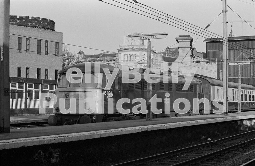 LPPC DSL BW 1219 
 The up side bays at the north end of Carlisle Citadel  seen behind the building on the left  used to be host to the stopping services to Glasgow via Dumfries and Kilmarnock and those to Edinburgh via Hawick and the Waverley Route. But the latter were long since finished when this shot of an AL5 Class 85 electric loco number 85034 was taken waiting to leave with a short passenger train. 
 Keywords: Digital, ISO, John Stiles