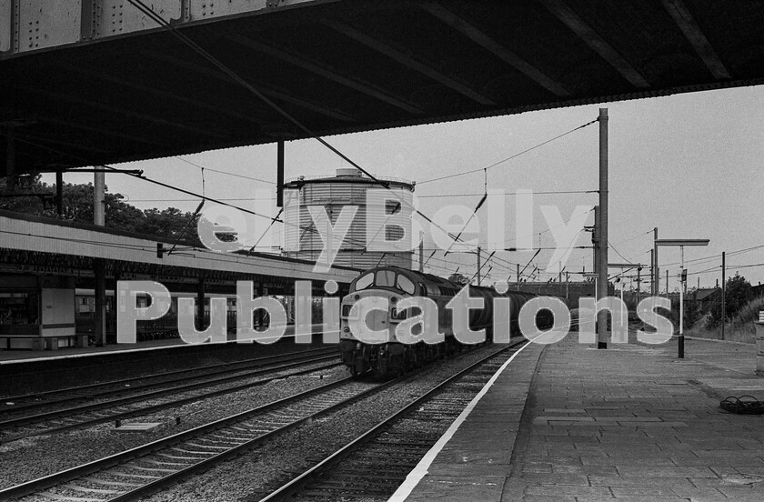 LPPC DSL BW 1148 
 A quiet moment late one morning in July 1975 on the West Coast Main Line at Lancaster station. The lull between passing West Coast Inter City traffic is filled by the sound of a member of station staff singing Cant Give You Anything by the Stylistics which was heading to number one at the time and a tank wagon train hurrying through, probably from nearby Heysham, passing on the up fast line headed by an English Electric Type 4 Class 40. In the bay on the far left is the DMU which ran in connection with Inter-City expresses for passengers to Morecambe, where once was the early overhead electric service to Heysham Harbour.