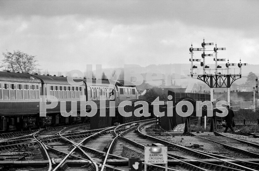 LPPC DSL BW 0710 
 In the early 1970s Western D1028 Western Hussar strikes out south from Exeter St Davids with a West of England express which consists of the usual rake of Mark 2 stock and a Full Brake (BG). The bracket-signal gantry is remarkable and sadly no longer with us. In the far distance on the right can just be made out the point where the freight spur line to Exeter City Basin diverges. At this time this was still a thriving and busy freight terminal  albeit of the type of which British Rail was very anxious to rid itself. 
 Keywords: BR, Western, Exeter St Davids, D1028, 'Western Hussar', Passenger