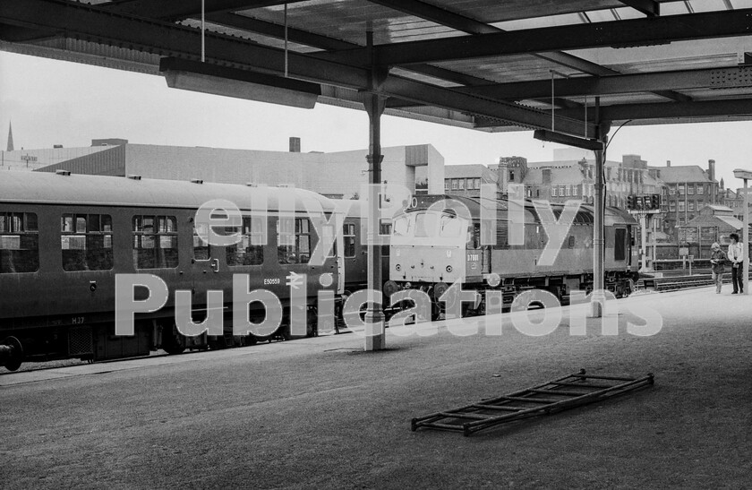 LPPC DSL BW 0940 
 Sulzer Class 25 D7601 (renumbered 25251 under TOPS in April, 1974) rests at Sheffield Midland station some time in the early 1970s. Still in BR Green it looks a little forlorn in its shabby condition, yet doesnt seem out of place. The Class 104 DMU was based at Hull Botanical Gardens at this time, and is too waiting for its next turn. The two spotters are walking down the platform taking notes and seem oblivious to the immediate danger they are in due to the unattended trestle ladders ahead of them...... can you imagine the uproar today? The Joseph Rodgers Cutlery Pond Street Works in the background was closed in 1968, but the building remained until 1984 before being demolished for a bus station. Late Summer 1973.