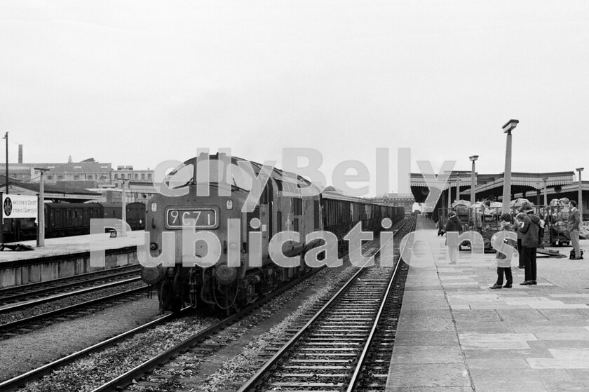 LPPC DSL BW 0785 
 An un-fitted rake of coal hoppers clatters through Cardiff General station on a centre road headed by an English Electric Type 3 Class 37 6988 (later 37288/37427)and watched by a clutch of spotters on the platform. The loco is filthy. So much so that it is difficult to discern the yellow nose. However, the Class 37s were worthy replacements for all the various GWR tank locos when it came to shifting many thousands of loaded and empty four-wheeled open wagons around the valleys and lines of South Wales for the best part of two decades. With the disappearance of vacuum-braked passenger rolling-stock, it was always interesting to check the formation of parcels trains. In the left background can be seen both ex-SR and LM vehicles as part of the consist of just such a working. 
 Keywords: BR, Western, Wales, Class 37, Cardiff Central, 6988, 37288, 37427, Coal, Freight, Spotters