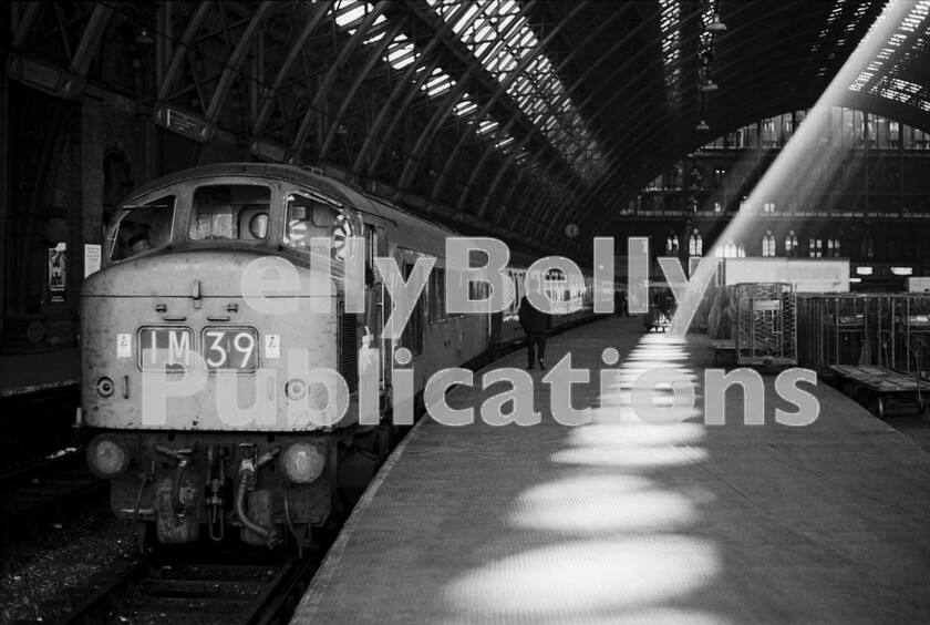 LPPC DSL BW 0599 
 In the traditions of pre-1950 photo reportage so evocatively published in magazines of the day  see C R L Coles, Liverpool Street station  I have always loved dramatic light and contrast situations, so this shot simply begged to be recorded. We believe the loco is Sulzer Type 4 Peak Class 45 D133 (later 45003) and the train is the 1M39 12.30 St Pancras to Nottingham semi-fast. These, very tightly timed between stops, trains were of limited load as can be seen and the 45s (and 46s) really came into their own during the 1970s recording some terrific performances almost as if the locos were maturing well with age like good wines. Note the amount of parcels traffic and Brutes on the platform whilst the Guard, having checked all is well with the loco and train, is heading back to his van to complete his journal details. 
 Keywords: Digital, Rights Managed, Stock