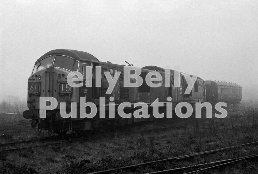 LPPC DSL BW 0968 
 A late 1971 foggy Sunday visit to Swindon Works finds two North British Loco company Type 2s awaiting the call from the scrap man. Number D6312 in the foreground is in original green livery and with as-built numbering, but has had the twin headcode boxes added later in its life, having originally sported headcodes by disc. Note the corridor connection doors in the centre of the nose fitted for when it would be hauling a train in multiple with one of its siblings. In contrast, the example behind, 6356, is one of the later 1100hp versions and displays its rail-blue livery with arrows and large side numbers. The Collett coach at the rear was a missed opportunity for preservationists! 
 Keywords: BR, Western, North British, Class 22, 6356, D6312, 1971, Scrap, Withdrawn, Swindon Works