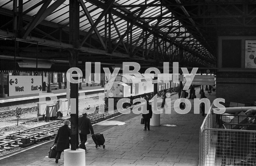 LPPC DSL BW 1186 
 At Bolton, passengers stir and walk towards, as they always do everywhere rather than wait for the train to stop near them, the Brush Type 4 Class 47 approaching from Manchester with an express for Glasgow. It will probably combine at Preston with a portion from Liverpool. Meanwhile, having to wait for the express to depart, for some time an English Electric Type 4 Class 40, either number 40124 or 40134, has been ringing and creeping its way on the through road with a rake of mineral wagons it is trying to keep the couplings taut, no doubt with the help of the guard at the rear. 
 Keywords: Digital, ISO, John Stiles