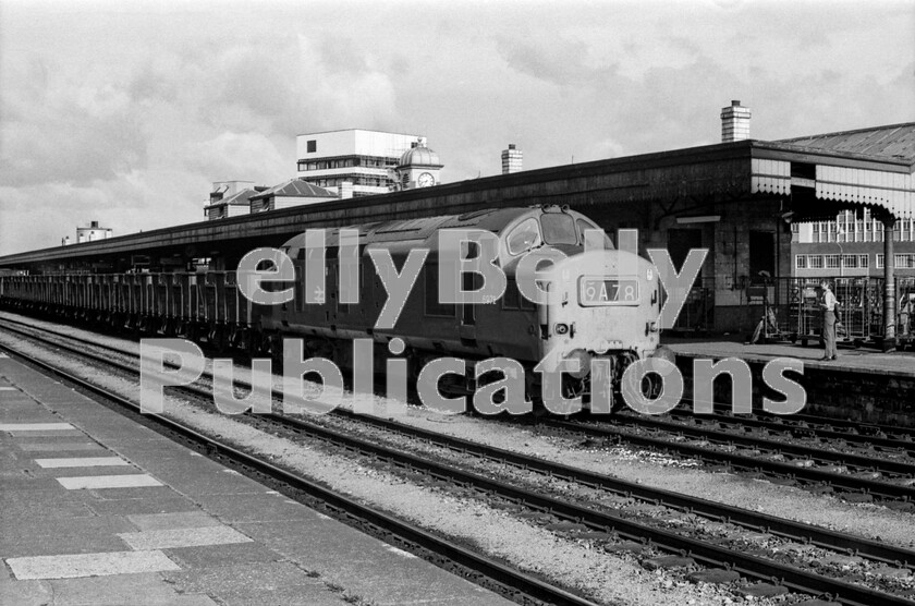 LPPC DSL BW 0572 
 A Saturday in the mid-1970s at Cardiff General station and an unusually smart English Electric Type 3 number 6972 (later 37272/37431) trundles empty coal hoppers along the up through centre road, probably returning from Aberthaw, using the triangular junction behind Canton MPD. These locos were numerous in South Wales for many years and as ubiquitous as their predecessors, the 56XX 0-6-2 tank engines. As always, a number of empty Brutes clutter up the platform in the background. Sometimes these left little room for passengers to make their way to their trains. 
 Keywords: BR, Western, Wales, Class 37, Freight, Coal, Cardiff Central, 6972, 37272, 47431