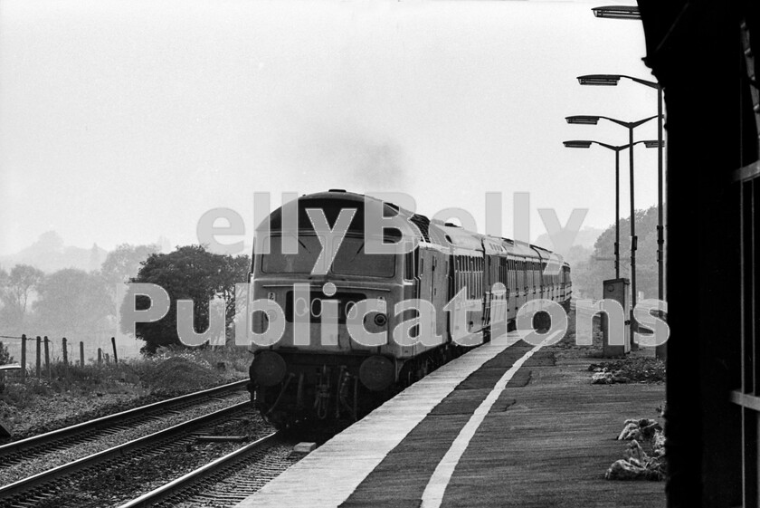 LPPC DSL BW 0406 
 Twyford station one summer Saturday afternoon in 1976 and Class 47, 47171, Brush Type 4 heads towards Paddington with the 1A15 10.30am Saturdays only service from Newquay to London. Already making well over 80mph after its Reading stop, the ride in one of the last-remaining wooden-bodied Gresley Buffet cars (W9135E) as the second vehicle here must have been an interesting experience. For many decades Twyford station required a 60mph, later raised to 75mph speed restriction on the main lines, as the route dog-legged around the signalbox and bridge abutments. This was all rectified in 1970 as the curves were eased and the platforms reshaped to allow for unrestricted speed. In this shot, the results can be clearly seen in the newly modified facings of the central island and newly laid track. 
 Keywords: BR, Twyford, Passenger, Class 47, 47171, 1A15, Gresley, Western, W9135E